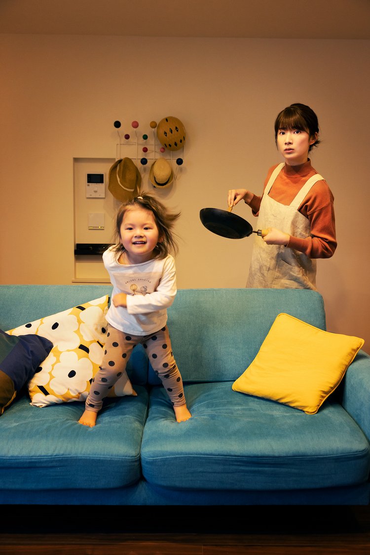フライパンを持った女性と飛び跳ねている子供